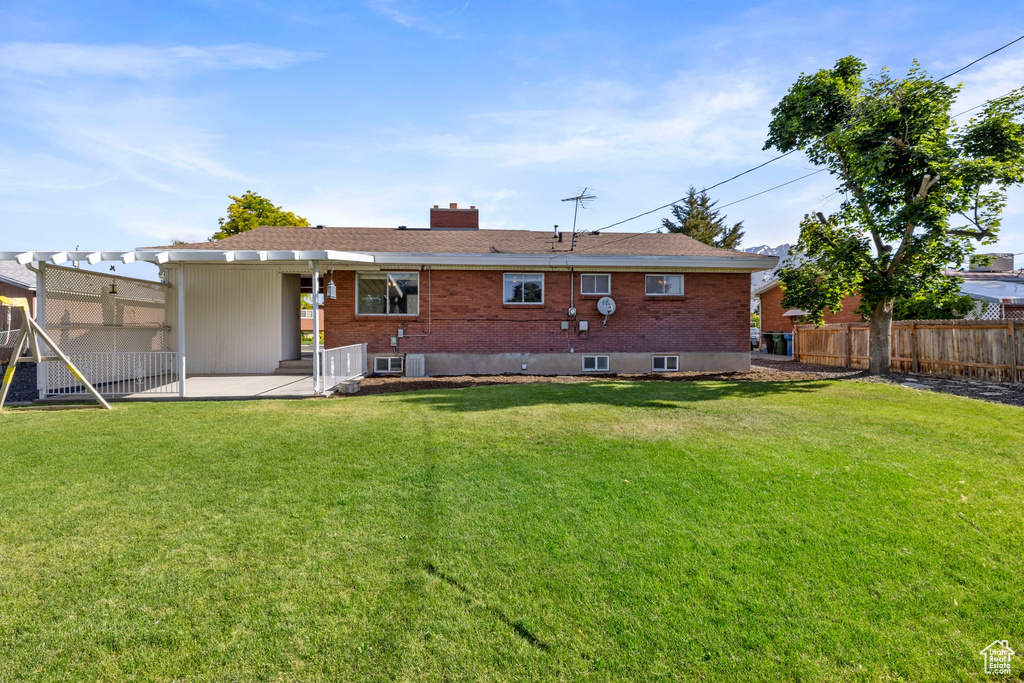 Rear view of house with a lawn and a patio