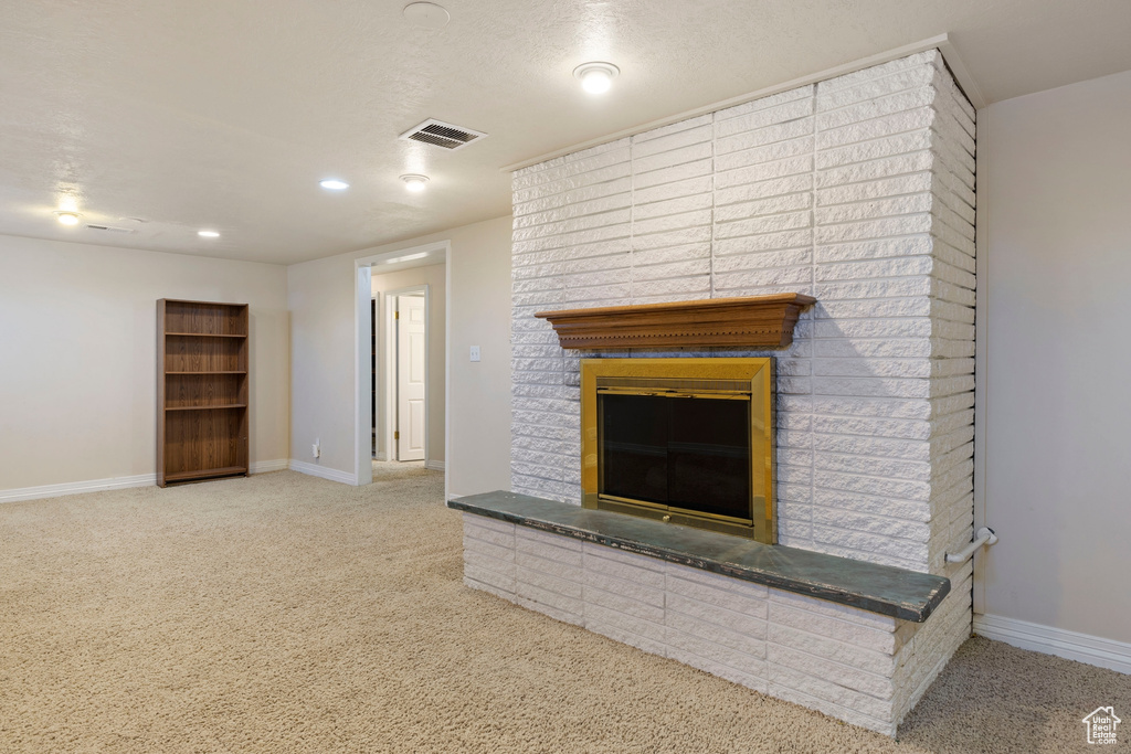 Unfurnished living room featuring carpet and a brick fireplace