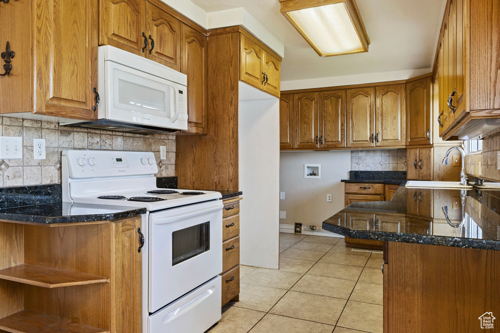 Kitchen featuring sink, tasteful backsplash, kitchen peninsula, white appliances, and light tile patterned floors