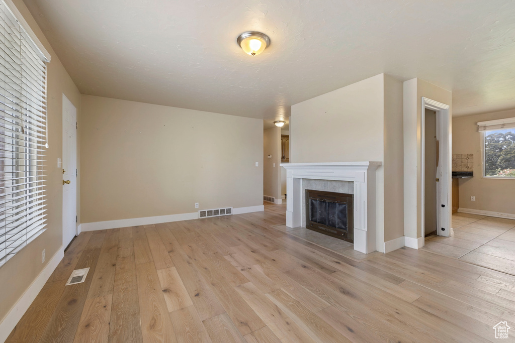 Unfurnished living room with a tile fireplace and light hardwood / wood-style flooring