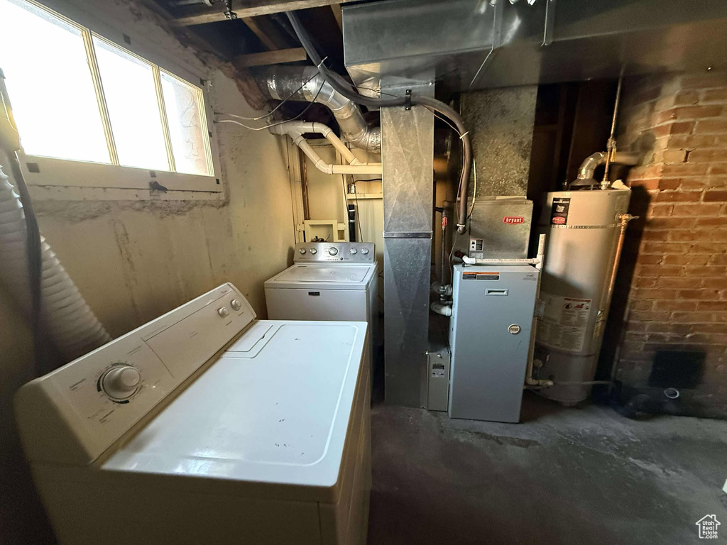 Washroom with washer and dryer, gas water heater, and brick wall