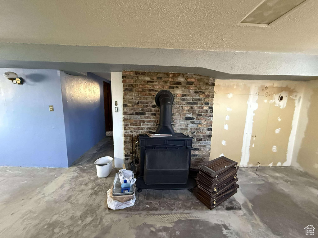 Details with concrete flooring, a textured ceiling, and a wood stove