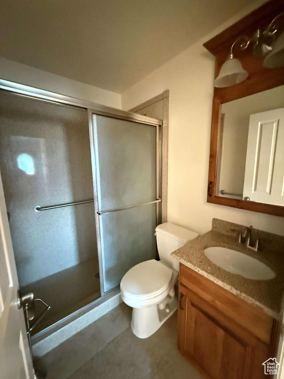 Bathroom featuring vanity, toilet, and a shower with shower door