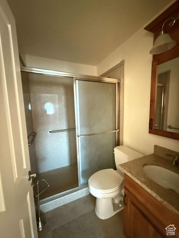 Bathroom with a shower with door, vanity, and toilet