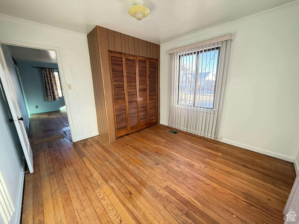 Unfurnished bedroom featuring crown molding, a closet, and light hardwood / wood-style floors