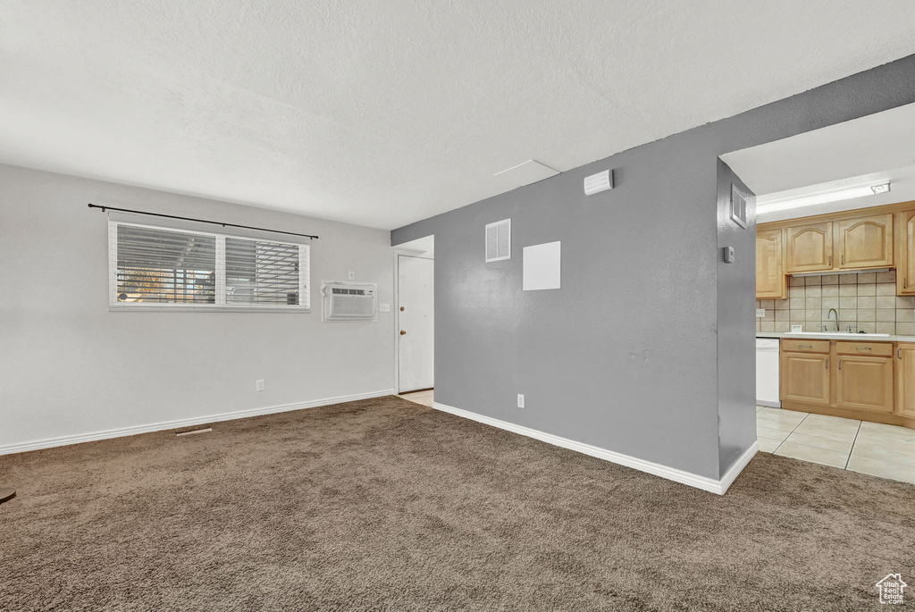 Carpeted spare room with a textured ceiling, a wall mounted AC, and sink