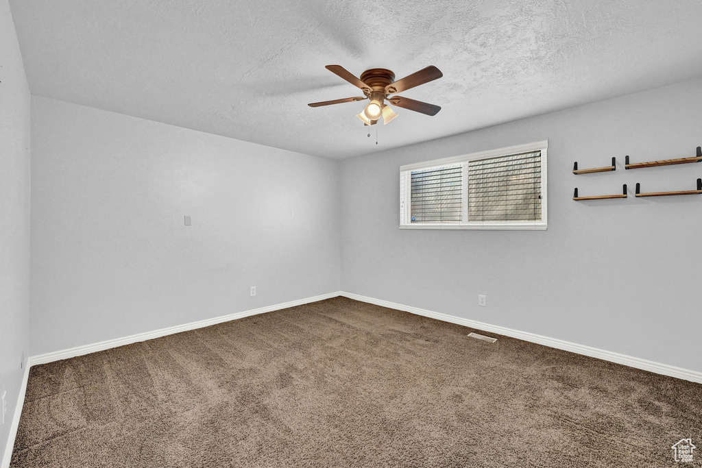 Unfurnished room featuring carpet, ceiling fan, and a textured ceiling