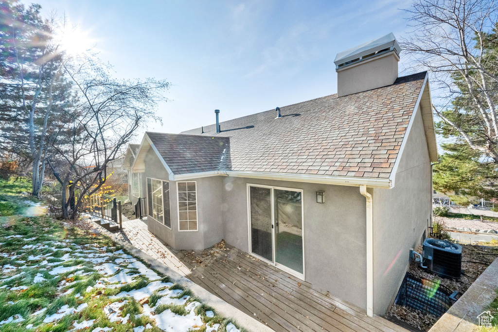 Rear view of property featuring central air condition unit and a wooden deck