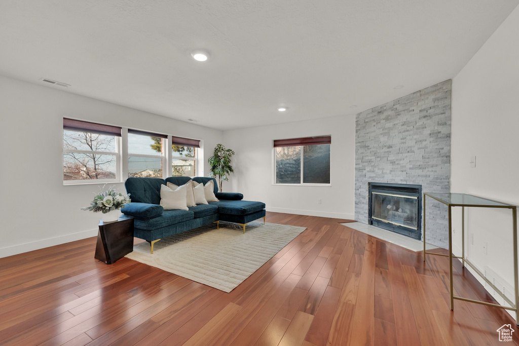 Living room with wood-type flooring and a stone fireplace