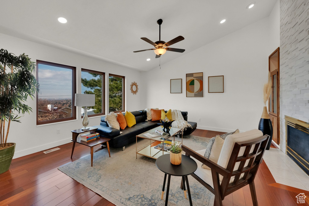 Living room with hardwood / wood-style floors, ceiling fan, lofted ceiling, and a fireplace