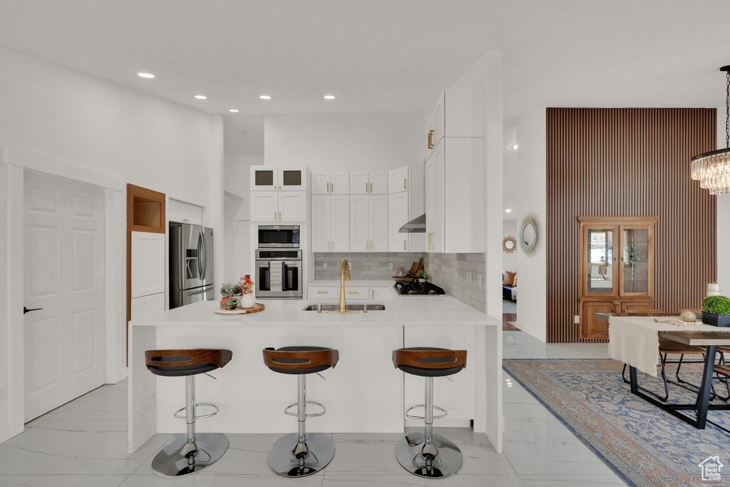 Kitchen featuring a breakfast bar, decorative light fixtures, stainless steel appliances, and sink