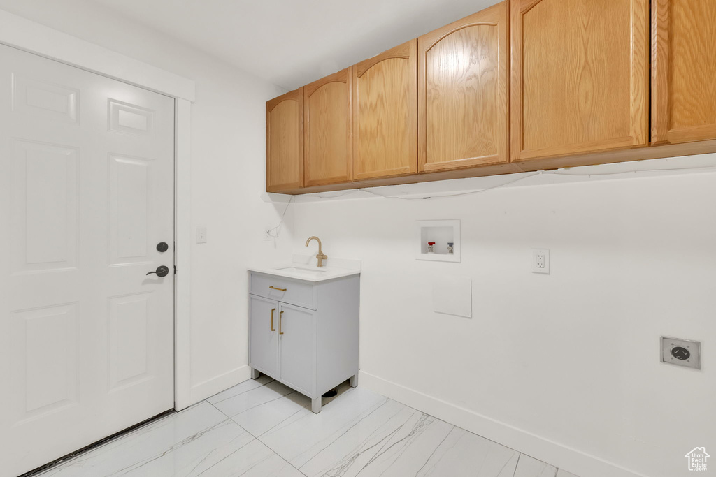 Laundry area with hookup for an electric dryer, hookup for a washing machine, cabinets, and sink