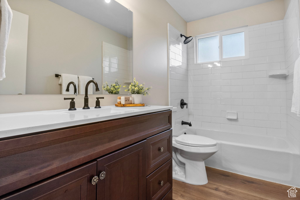 Full bathroom with hardwood / wood-style flooring, vanity, toilet, and tiled shower / bath