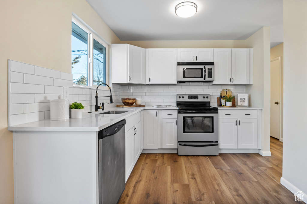 Kitchen with backsplash, white cabinetry, sink, and stainless steel appliances