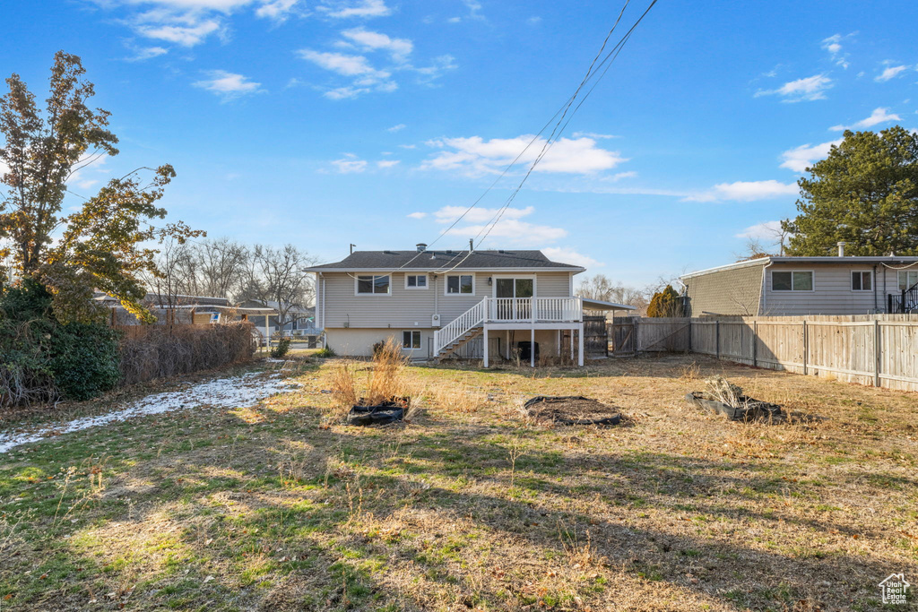 Rear view of property featuring a wooden deck and a lawn