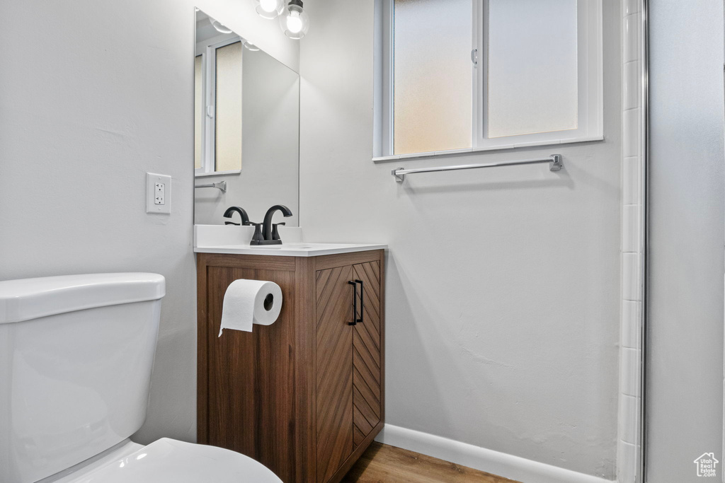 Bathroom featuring hardwood / wood-style flooring, vanity, toilet, and an enclosed shower