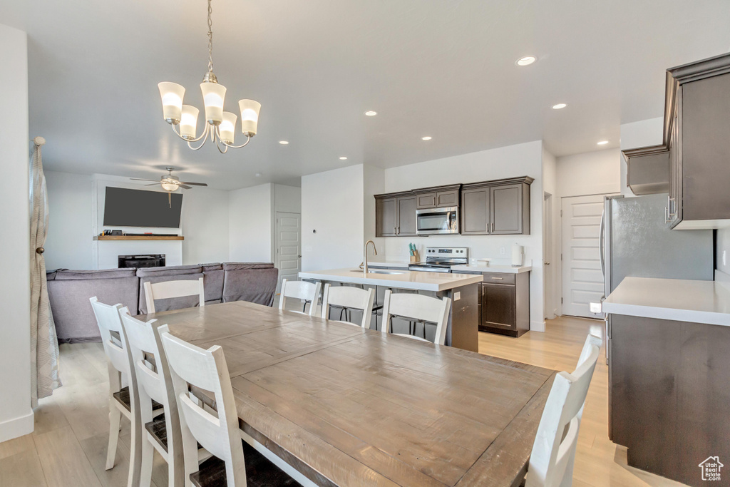 Dining space with ceiling fan with notable chandelier, light hardwood / wood-style flooring, and sink