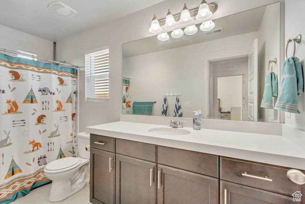 Bathroom featuring a shower with shower curtain, vanity, and toilet