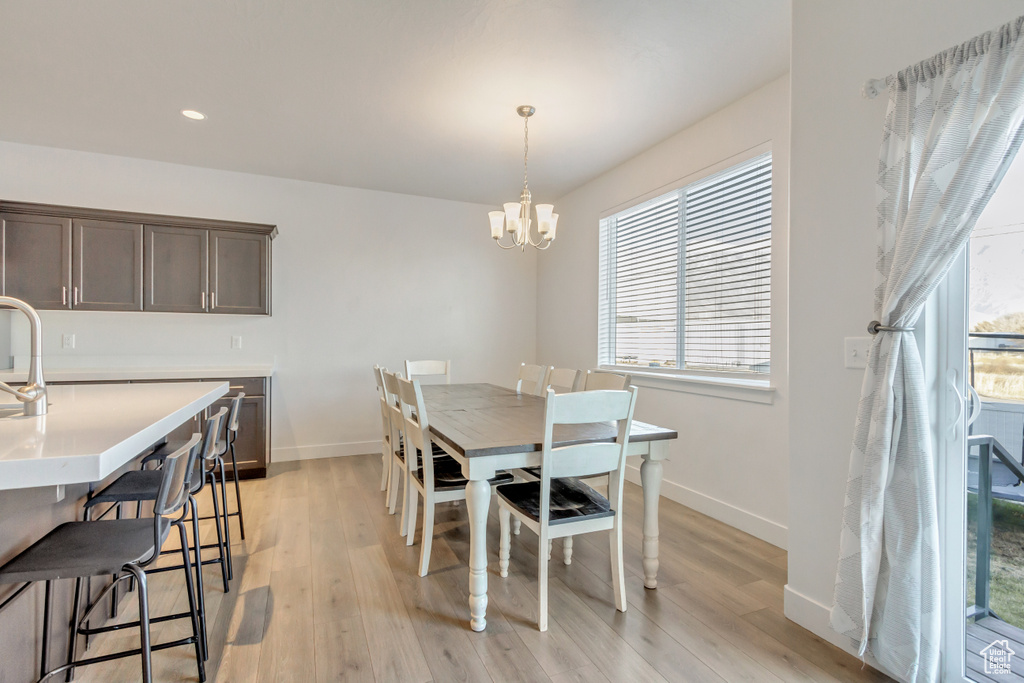 Dining area with sink, an inviting chandelier, and light wood-type flooring