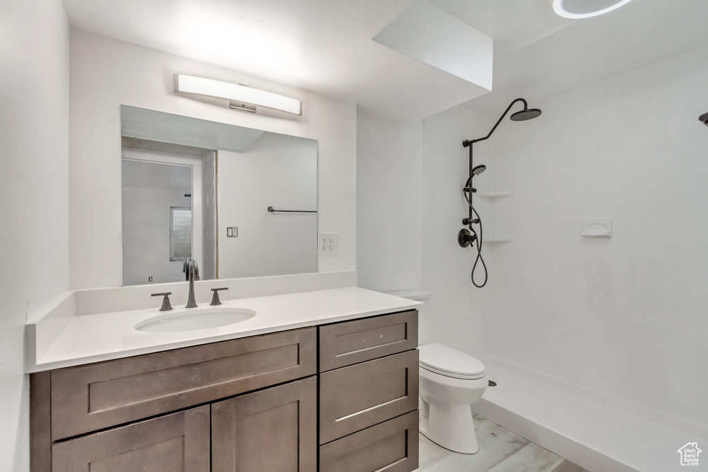 Bathroom featuring a shower, vanity, and toilet