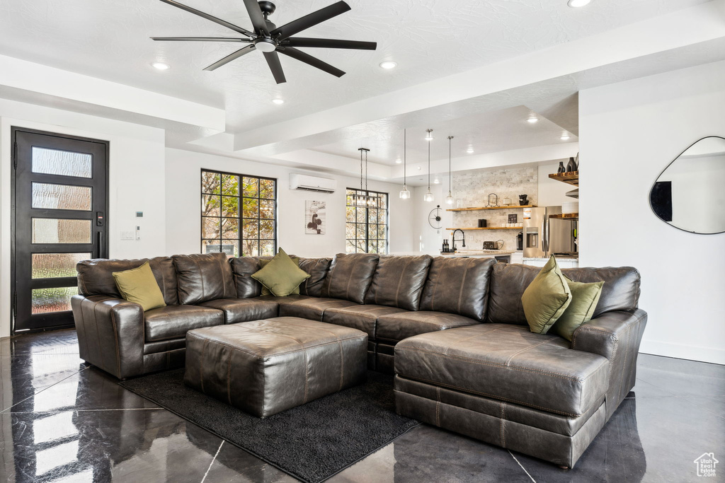 Living room with a raised ceiling, a wall unit AC, ceiling fan, and sink