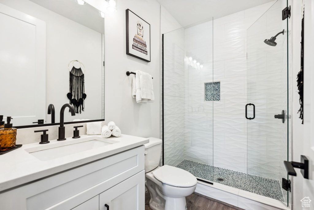 Bathroom with hardwood / wood-style flooring, vanity, toilet, and a shower with door