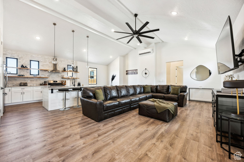 Living room with ceiling fan, sink, light hardwood / wood-style flooring, a wall mounted AC, and vaulted ceiling