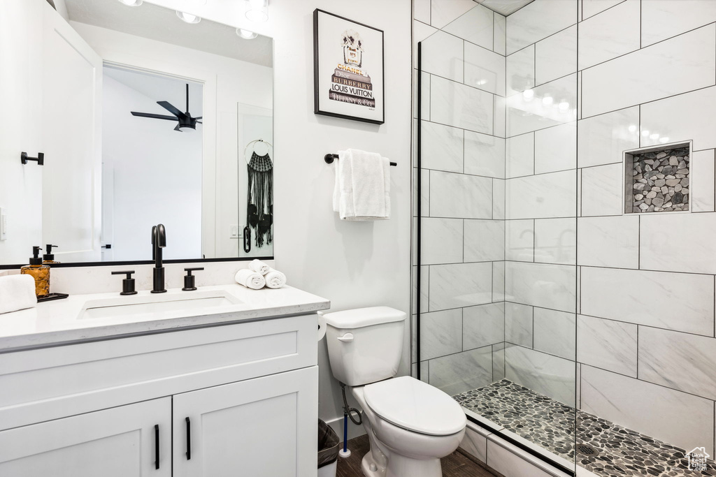 Bathroom featuring vanity, toilet, and a tile shower