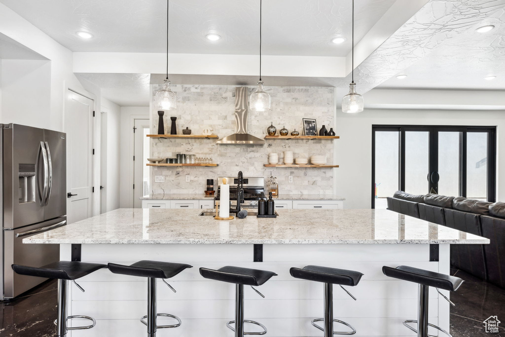 Kitchen with a kitchen breakfast bar, light stone countertops, decorative light fixtures, and stainless steel refrigerator with ice dispenser