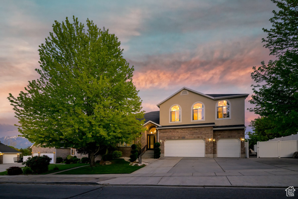 View of front of property featuring a garage, concrete driveway, and stucco siding
