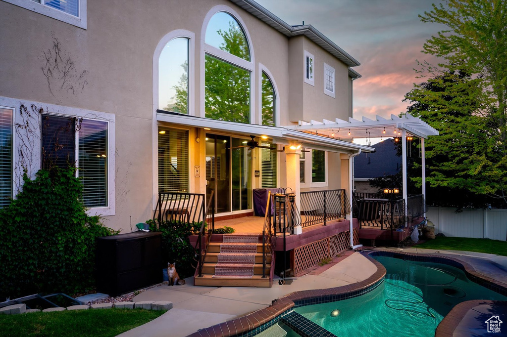 Rear view of property with stucco siding, a deck, and a pergola