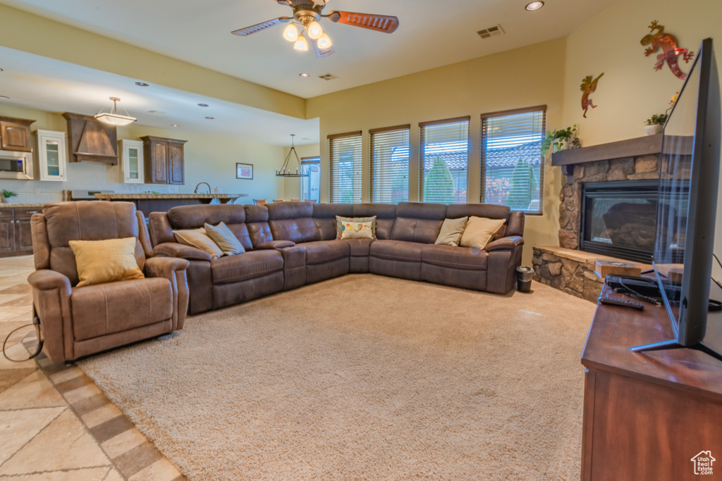 Living room with ceiling fan, a fireplace, and light carpet