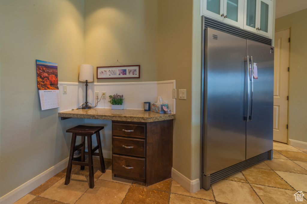 Kitchen with a breakfast bar, built in fridge, kitchen peninsula, dark brown cabinets, and white cabinetry