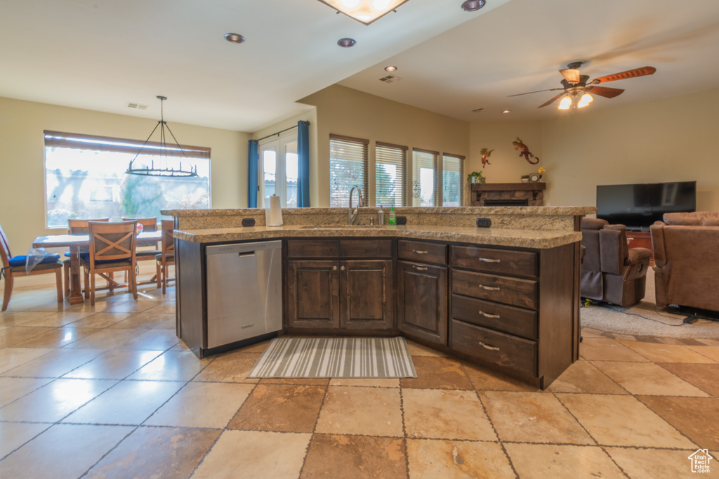 Kitchen with dark brown cabinetry, dishwasher, sink, pendant lighting, and a kitchen island with sink
