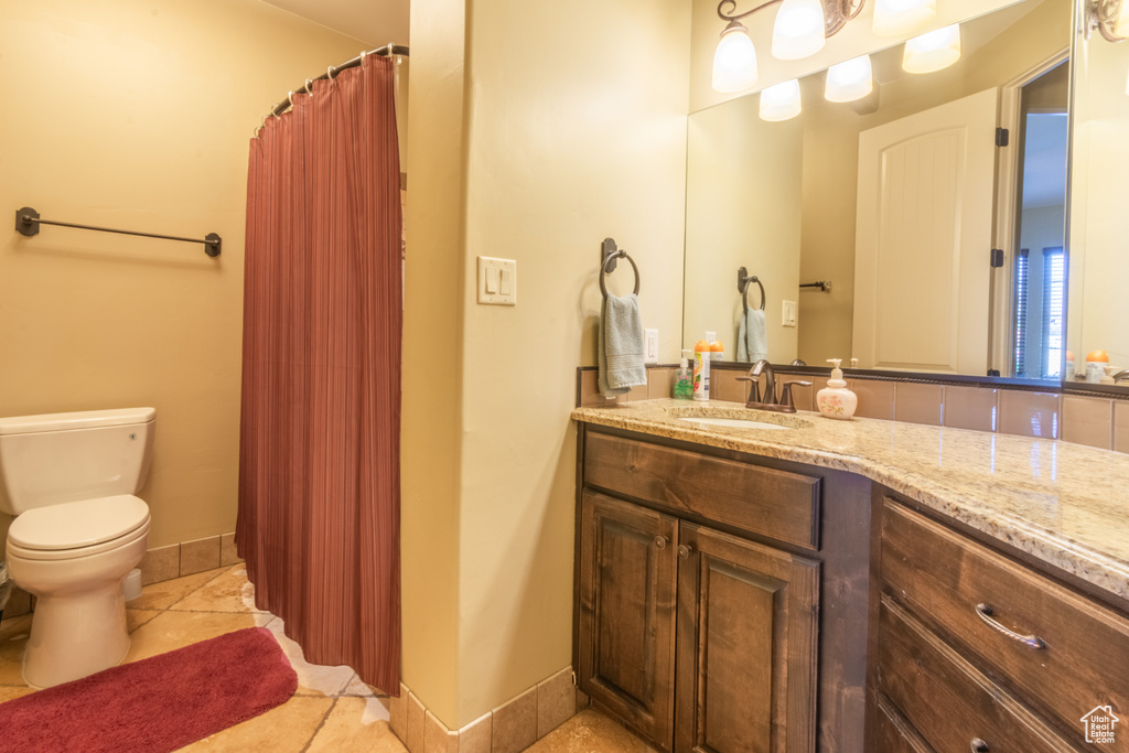 Bathroom featuring tile patterned floors, vanity, toilet, and walk in shower