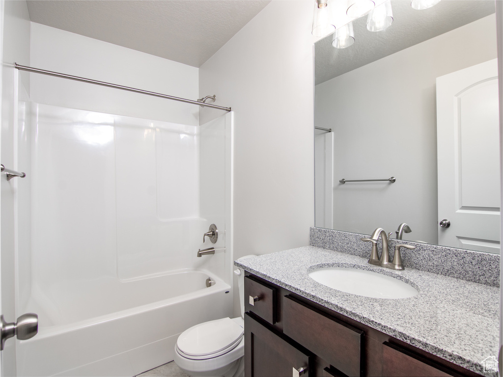 Full bathroom featuring vanity, toilet, a textured ceiling, and bathtub / shower combination