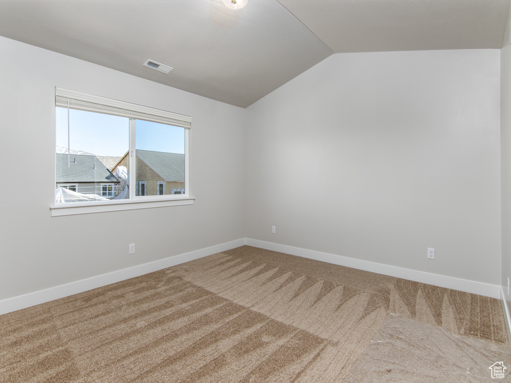 Carpeted spare room with lofted ceiling