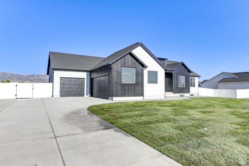 Modern farmhouse with a mountain view, a garage, and a front lawn