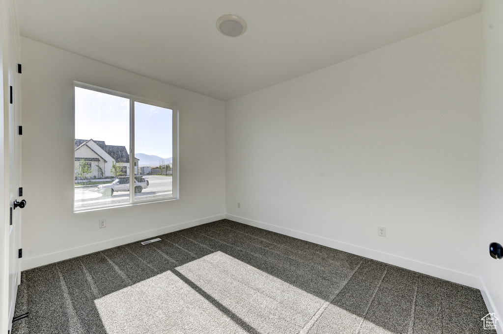 Unfurnished room featuring dark colored carpet