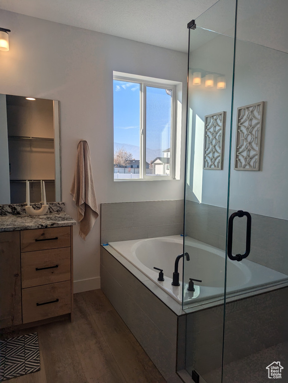 Bathroom featuring hardwood / wood-style floors, vanity, and shower with separate bathtub