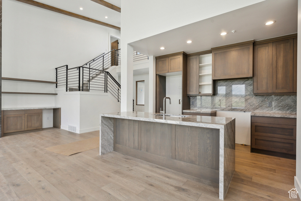 Kitchen with a sink, decorative backsplash, high vaulted ceiling, light wood-style flooring, and recessed lighting