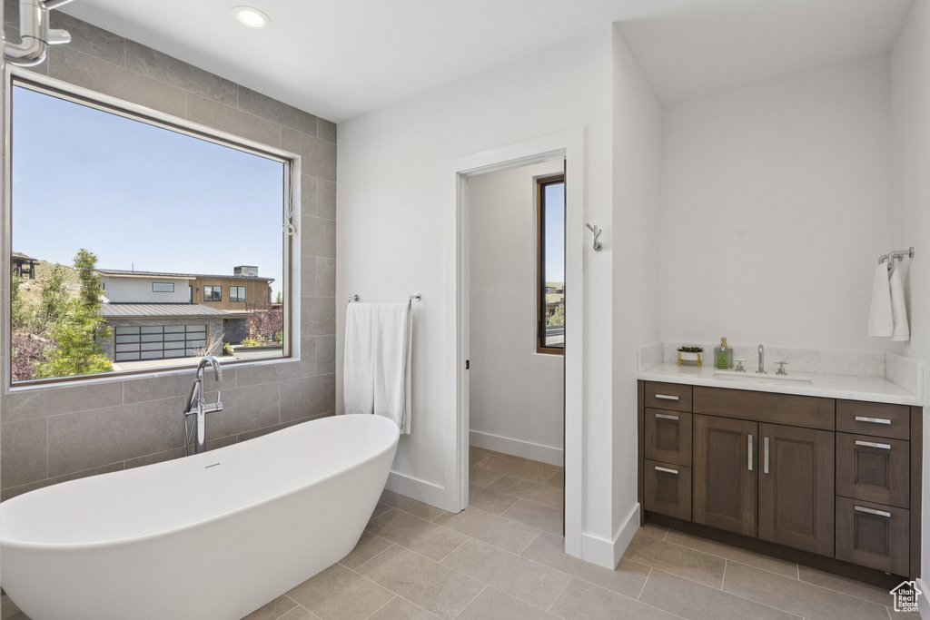 Full bath with a freestanding bath, healthy amount of natural light, vanity, tile patterned flooring, and recessed lighting