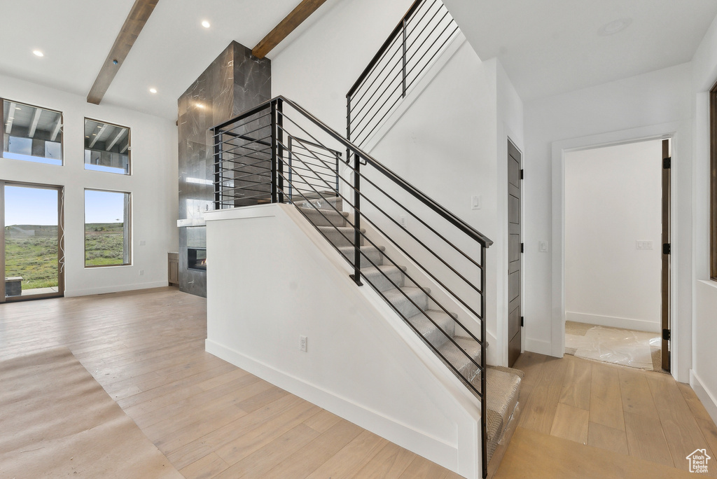 Staircase featuring a large fireplace, wood finished floors, baseboards, beamed ceiling, and recessed lighting