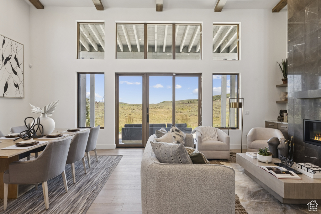Living area with beamed ceiling, a tile fireplace, a high ceiling, and wood finished floors
