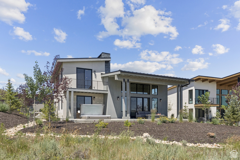 Rear view of property featuring a balcony and stucco siding