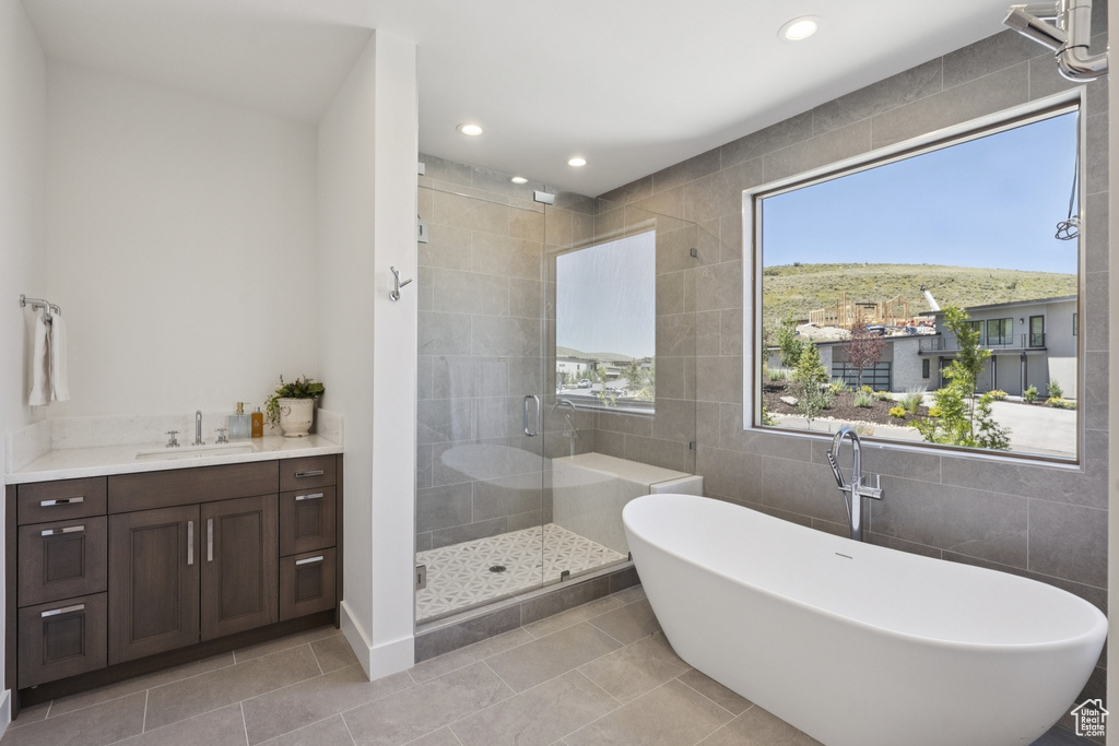 Bathroom featuring tile walls, a freestanding tub, a shower stall, tile patterned flooring, and recessed lighting