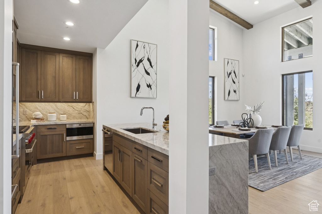 Kitchen with light stone counters, light wood-type flooring, recessed lighting, tasteful backsplash, and high end stove