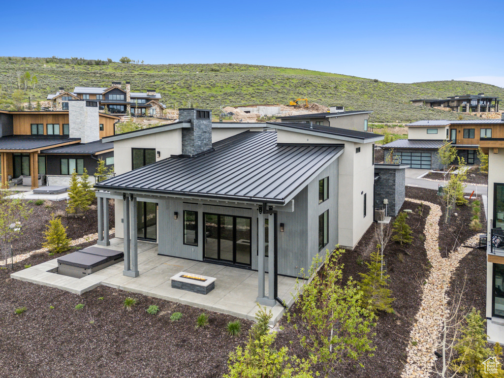 Rear view of property featuring a standing seam roof, metal roof, a chimney, a patio, and a mountain view