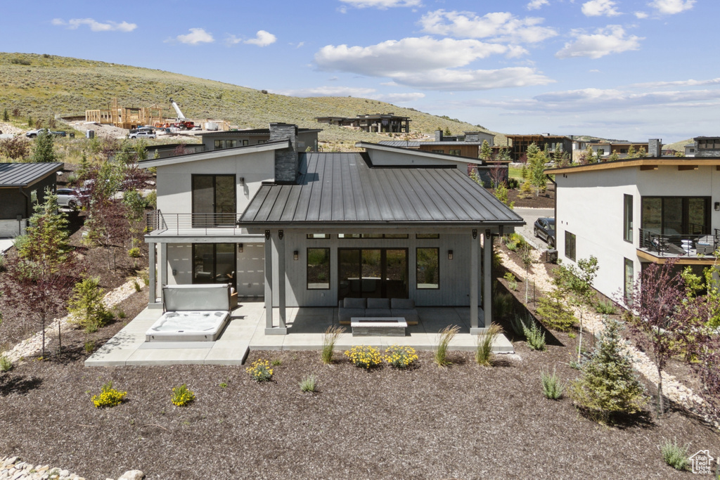 Rear view of house with a standing seam roof, a metal roof, a balcony, a patio area, and a mountain view