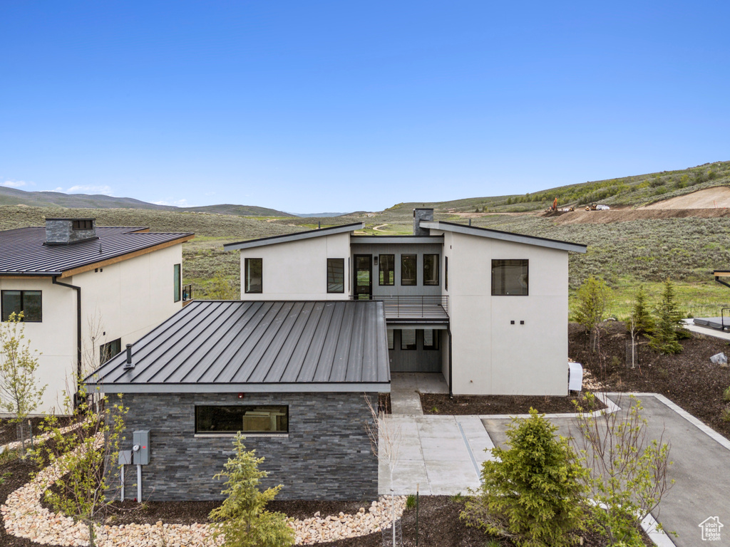 Back of house with a standing seam roof, a mountain view, metal roof, and stucco siding